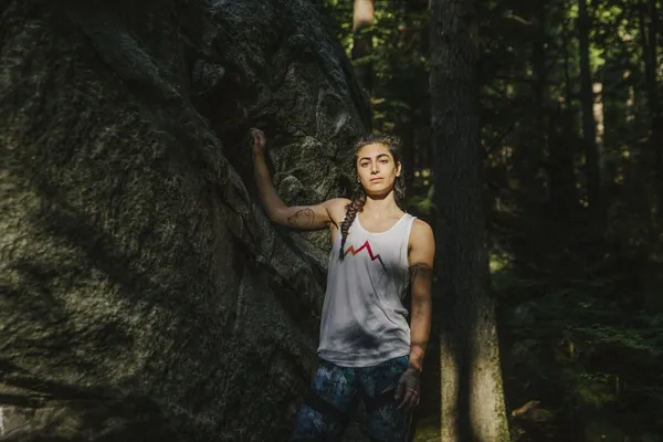 Someone standing next to a large rock cliff or boulder
