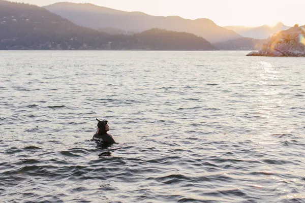 Someone swimming, with low mountains nearby