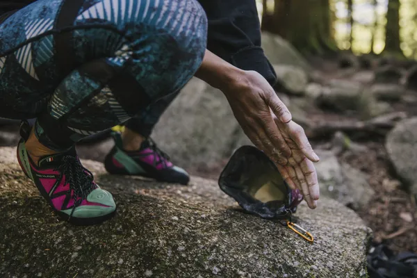 A person crouched down applying chalk to their hands