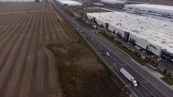 Overhead view of highway next to farmlands and large Amazon warehouse