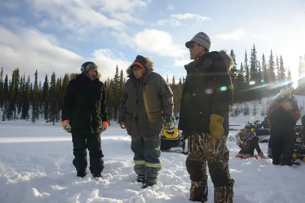 Three people outside in the snow, sharing stories of fishnet setting