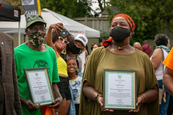 Two people having their work feeding their community commemorated by a local MPP
