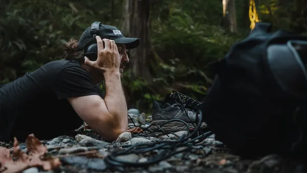 Man listening to recordings while prone in the forest